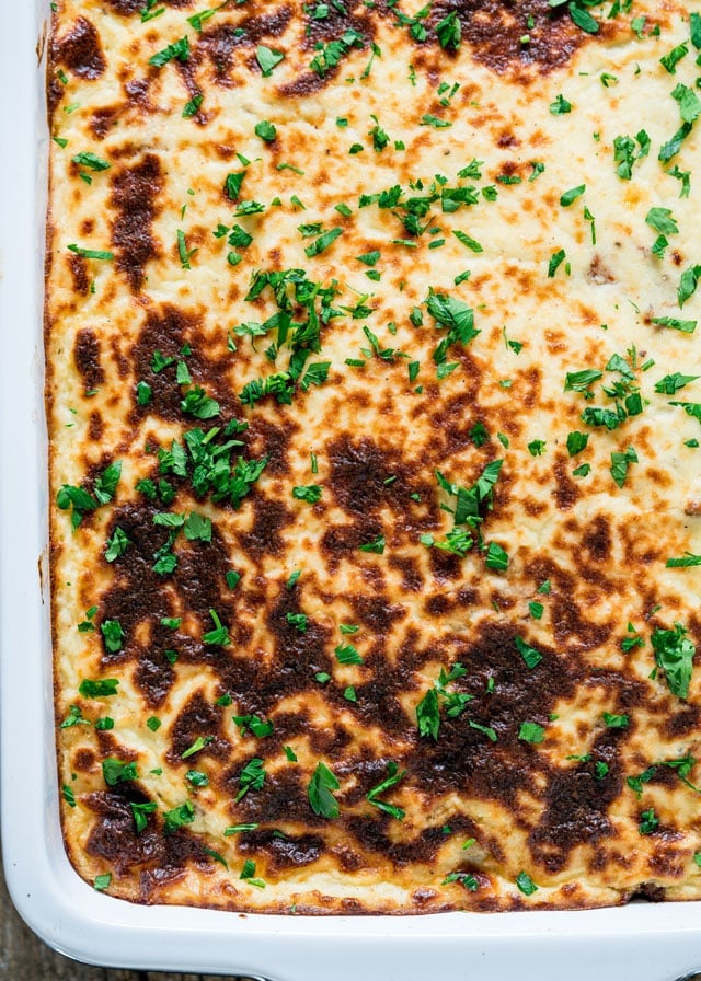 overhead of a baking dish filled with moussaka and topped with fresh parsley