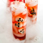 side view shot of glasses of witches brew with decorative skulls floating in the drink. The glasses are surrounded by smoke