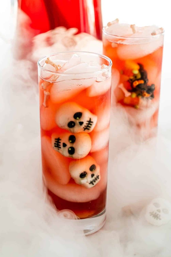 side view shot of glasses of witches brew with decorative skulls floating in the drink. The glasses are surrounded by smoke