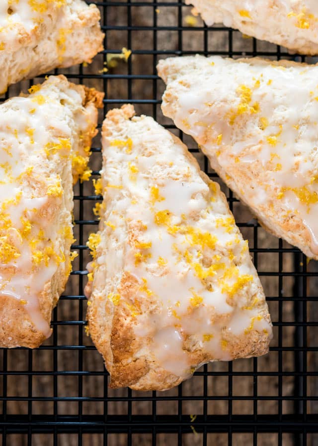 scones coated in glaze and lemon zest cooling on a rack