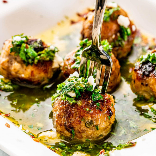 close up shot of chimichurri meatballs on a plate with a fork stabbed into one of them
