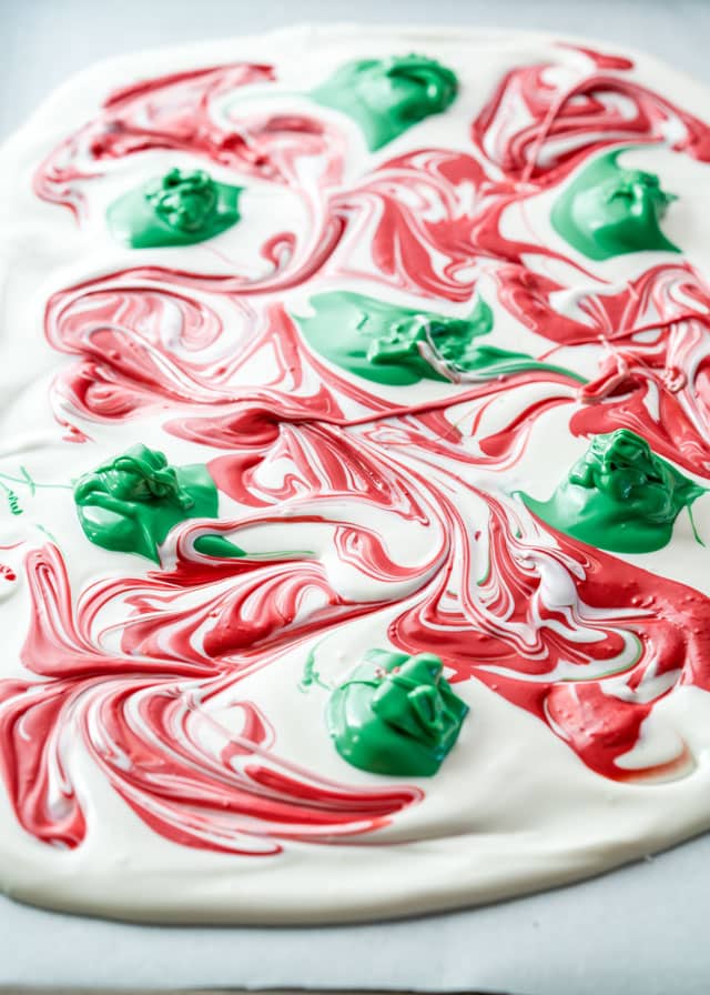 a layer of white chocolate with dollops of green chocolate and swirls of red chocolate