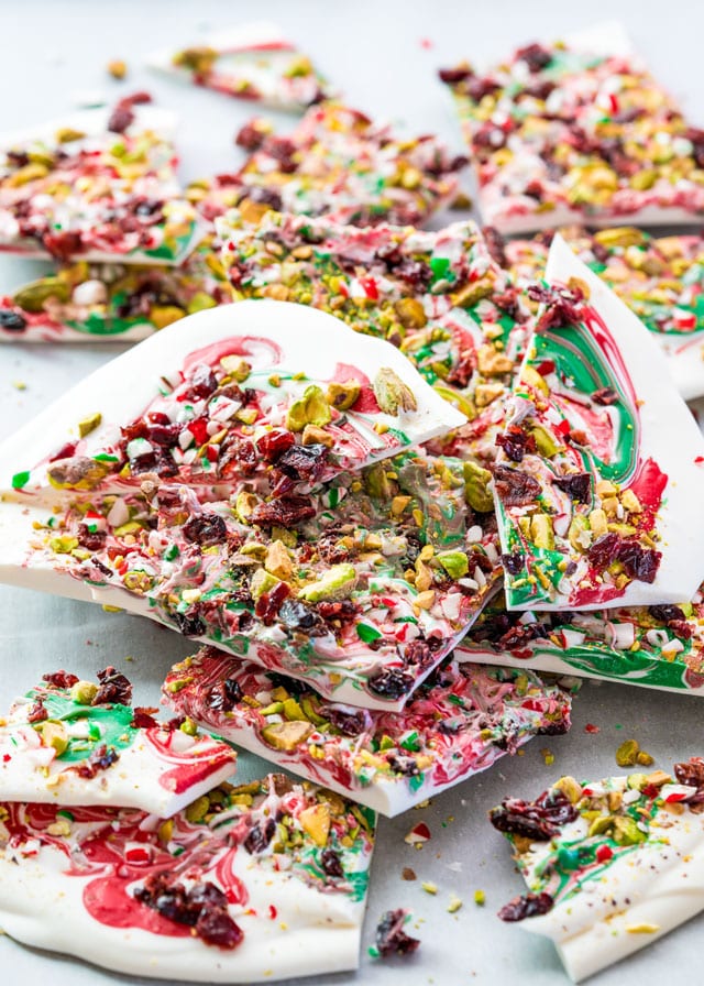 a pile of white, red and green candy cane bark covered in nuts and cranberries