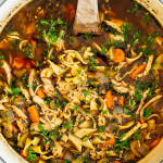 overhead shot of a pot of flu fighter chicken noodle soup with a wooden spoon in it