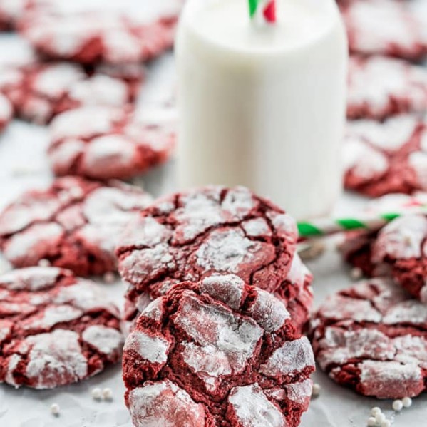 side view shot of red velvet crinkle cookies surrounding a glass of milk