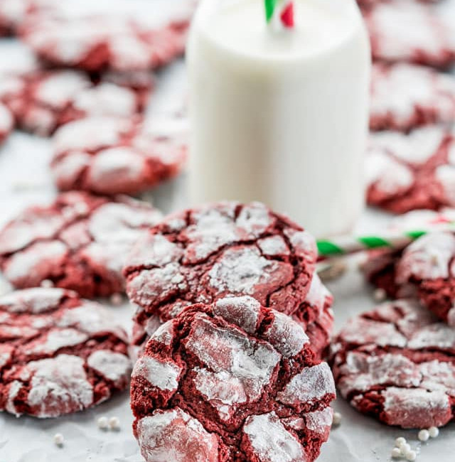 side view shot of red velvet crinkle cookies surrounding a glass of milk