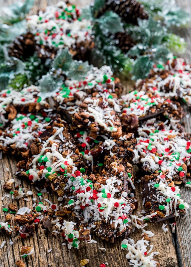 chocolate bark broken into pieces topped with cashews, coconut, and sprinkles over a wooden table