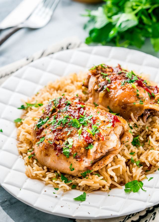 a plate of roasted chicken thighs over rice