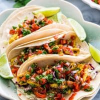 3 vietnamese fish tacos on a plate garnished with lime wedges