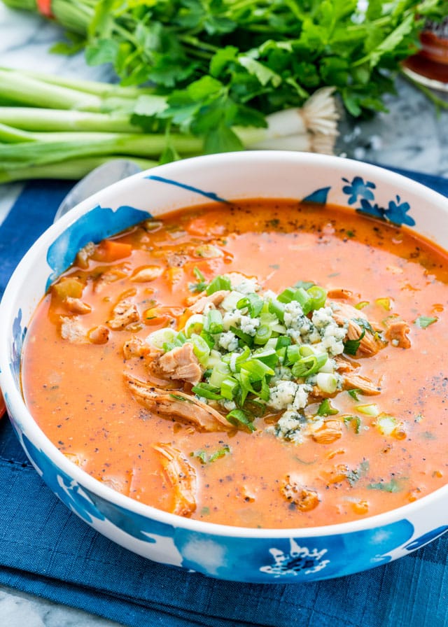 a bowl of soup with chicken topped with blue cheese and green onions