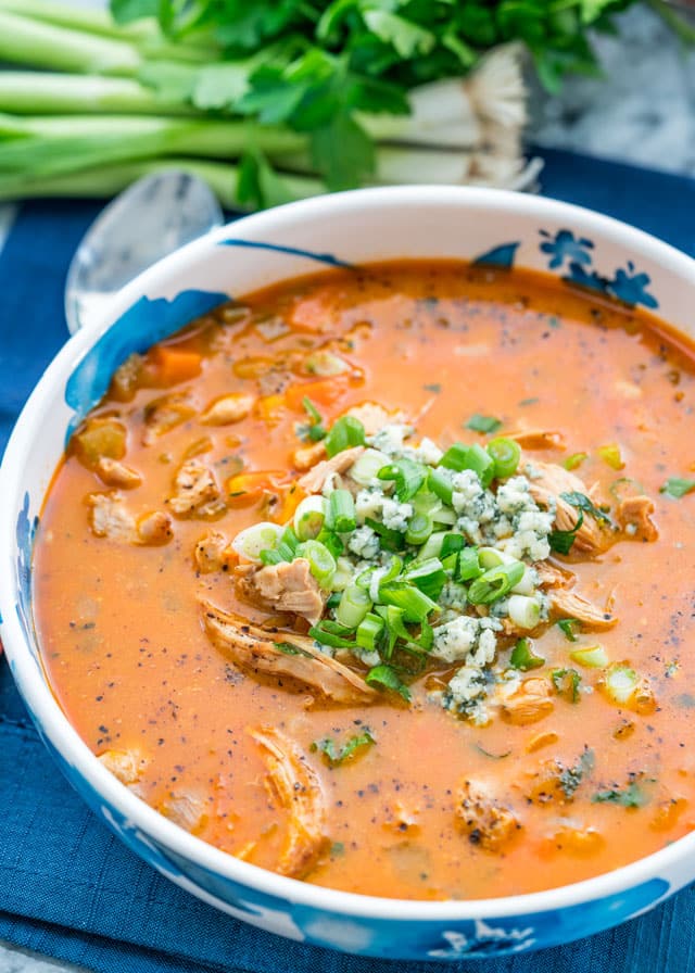 a bowl full of soup with chicken, blue cheese, and green onion.