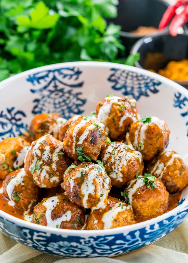 a bowl of meatballs covered in sauce and parsley