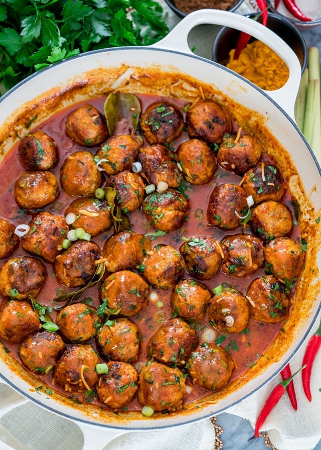 overhead of a braiser full of meatballs in sauce with parsley and green onion