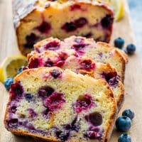 sliced lemon blueberry loaf on a cutting board garnished with fresh blueberries