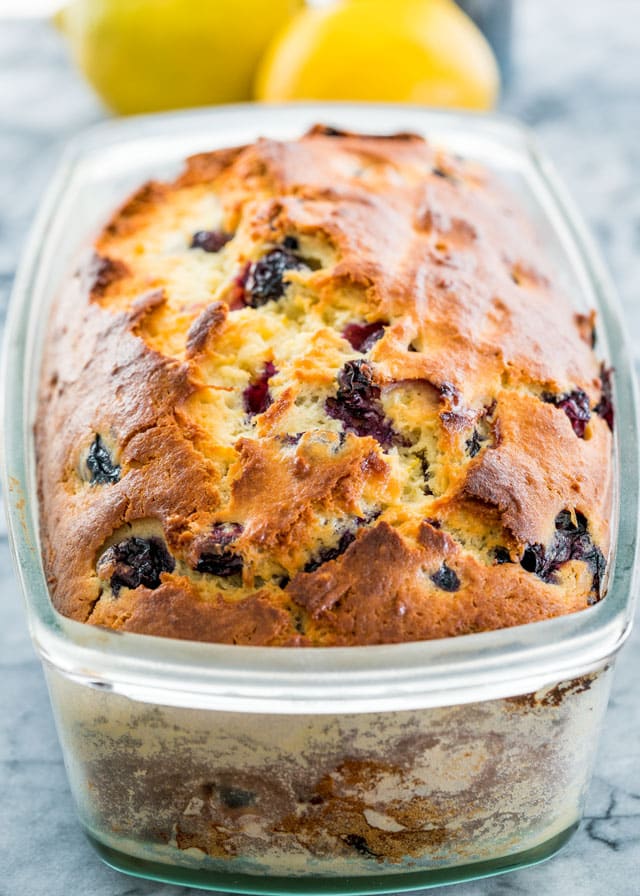 blueberry lemon loaf in a glass pan fresh out of the oven with a crackled golden brown surface