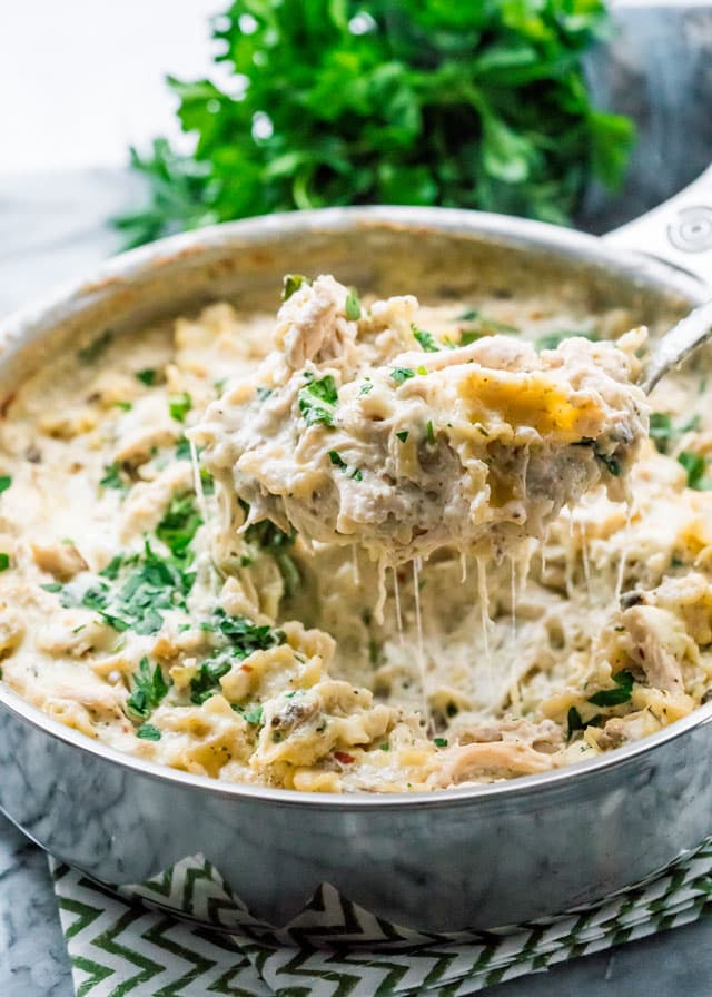 a pan filled with cheesy chicken white lasagna topped with parsley