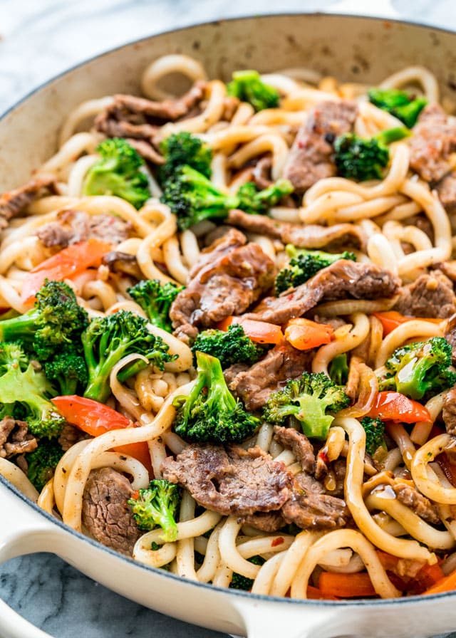 closeup of a noodle stir fry with beef, broccoli, and red pepper in a braiser