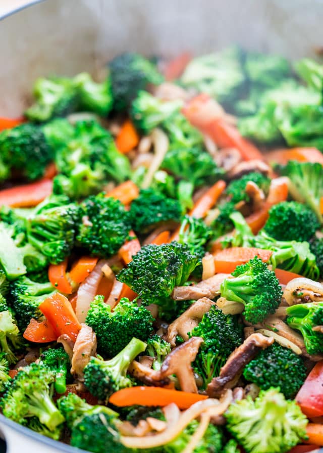 broccoli, mushrooms, and red pepper sizzling in a pan