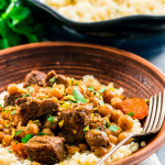 side view shot of a bowl of couscous topped with lamb and chickpea tagine