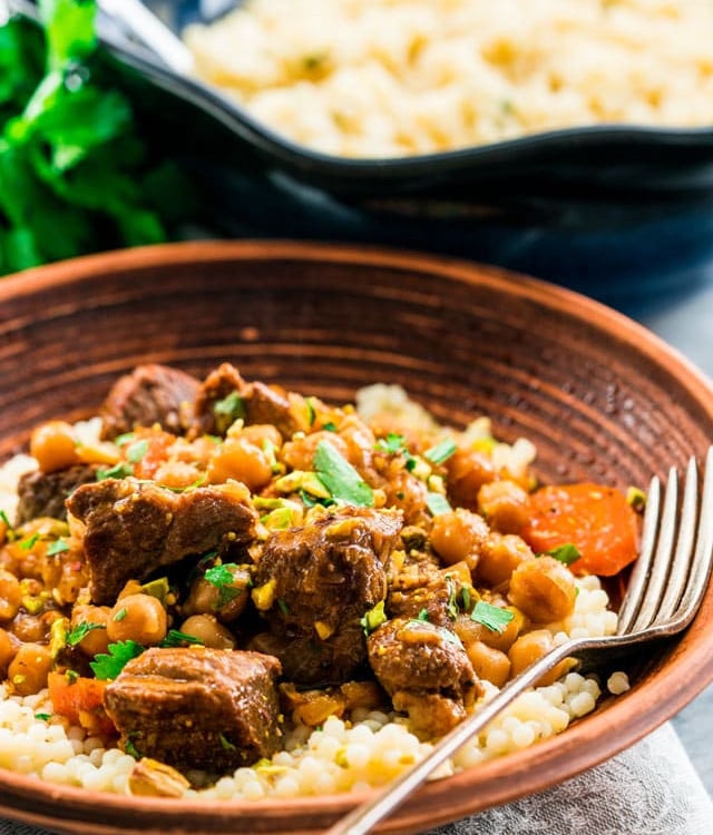 side view shot of a bowl of couscous topped with lamb and chickpea tagine