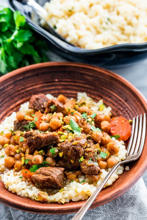 side view shot of a bowl of couscous topped with lamb and chickpea tagine