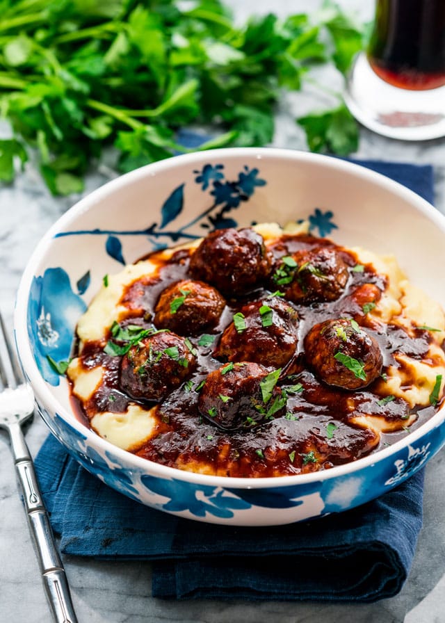 a bowl of meatballs over mashed potatoes with tons of sauce