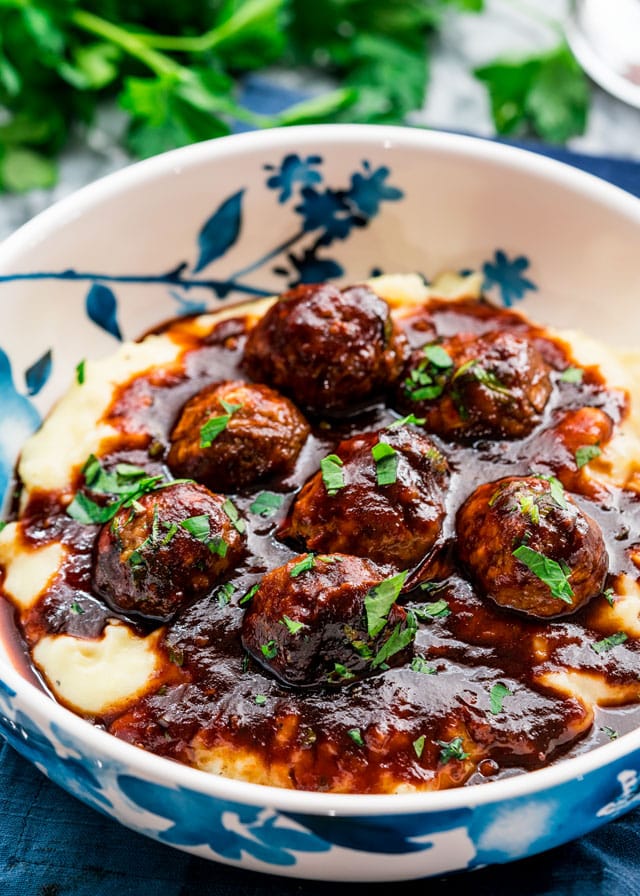 a bowl full of meatballs over mashed potatoes covered in sauce