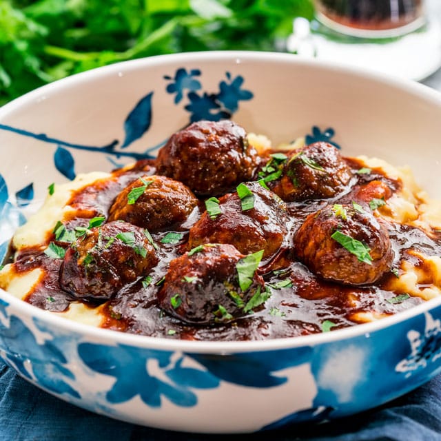 closeup of a bowl of meatballs over mashed potatoes covered in sauce