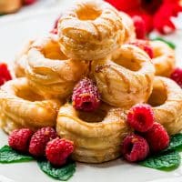 side view shot of a pyramid of dulce de leche cronuts on a plate garnished with fresh raspberries and mint leaves