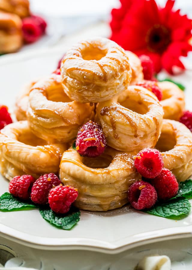a plate piled with cronuts with mint and raspberries drizzled with dulce de leche