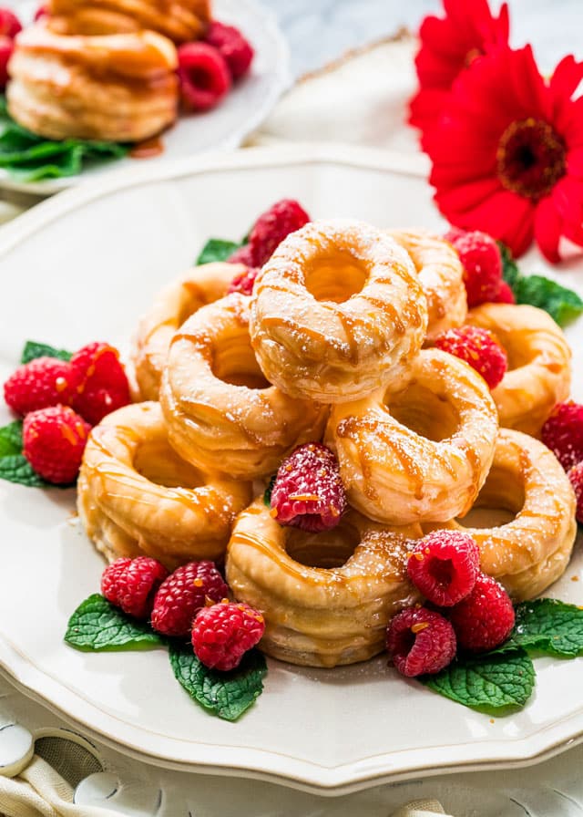 a plate filled with cronuts with mint, raspberries, and drizzled with caramel
