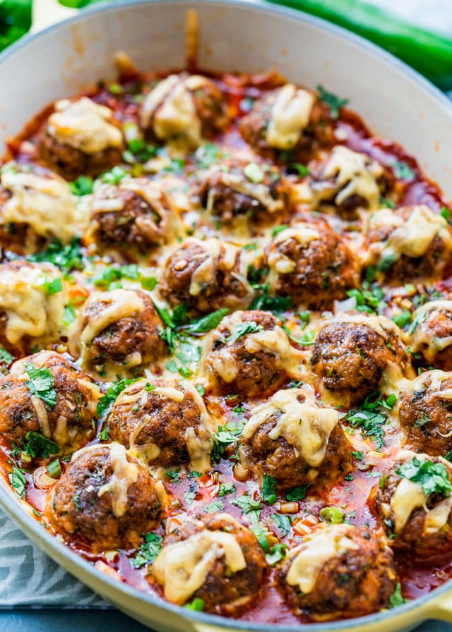 meatballs covered in enchilada sauce and melted cheese in a casserole dish