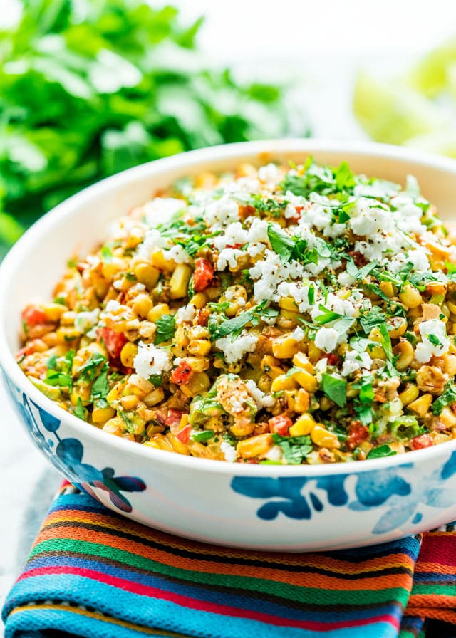Mexican Street Corn Salad in a bowl topping with cotija cheese and parsley