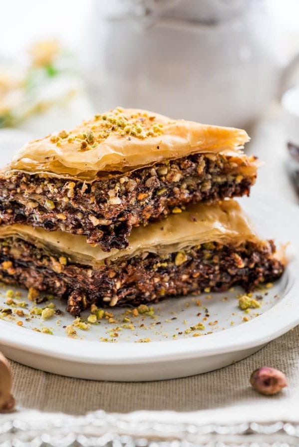 side view close up shot of two pieces of chocolate baklava stacked on a plate