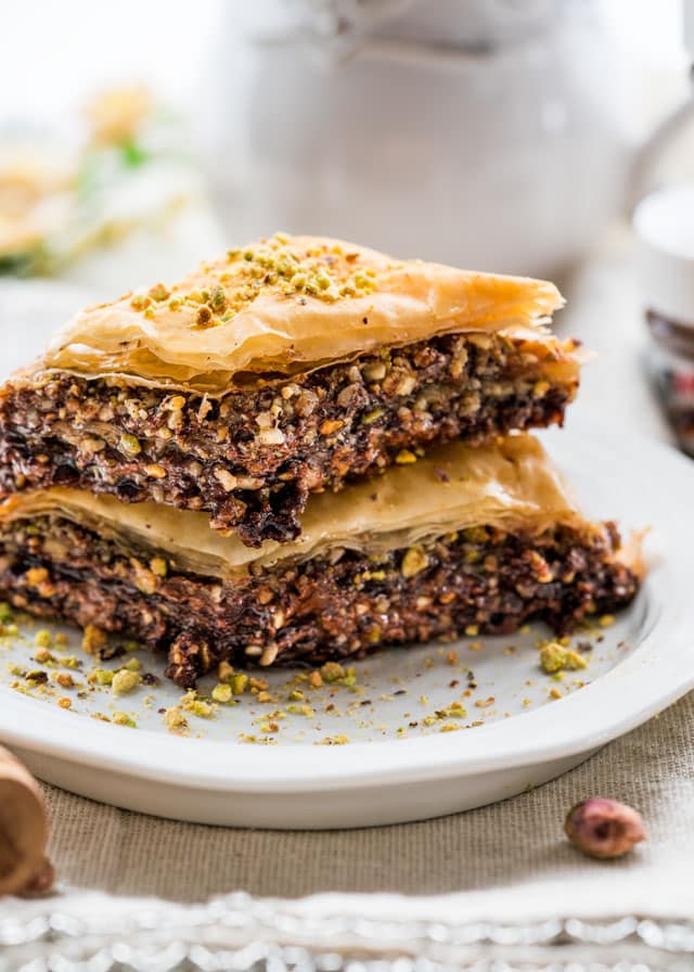 side view close up shot of two pieces of chocolate baklava stacked on a plate