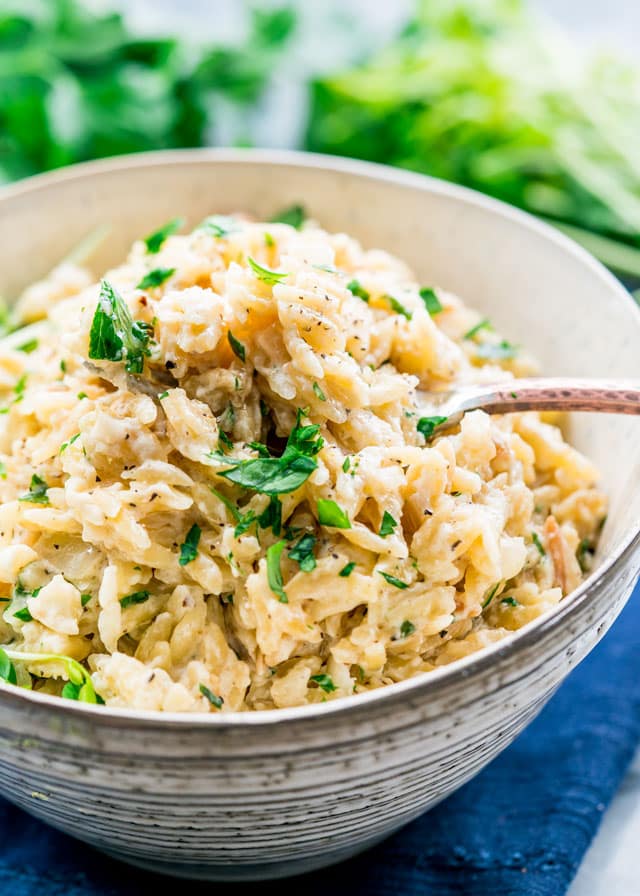 a bowl of creamy parmesan orzo with a fork and parsley