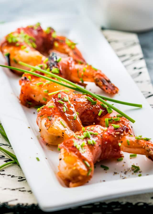 bacon wrapped shrimp on a small plate topped with chives