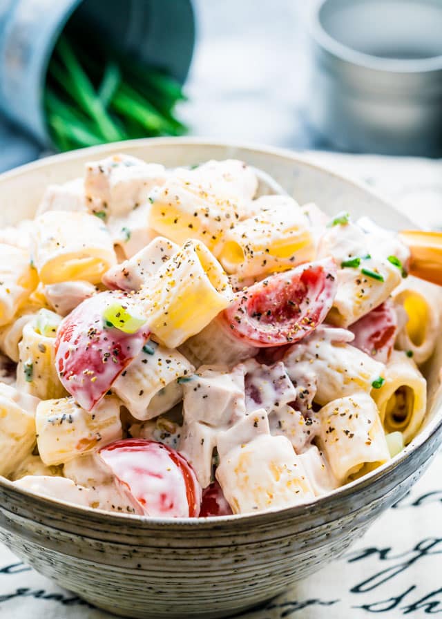 pasta salad in a bowl with tomatoes topped with pepper