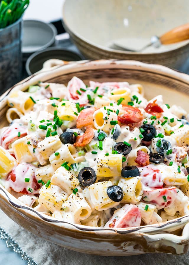 pasta salad in a serving bowl topped with olives