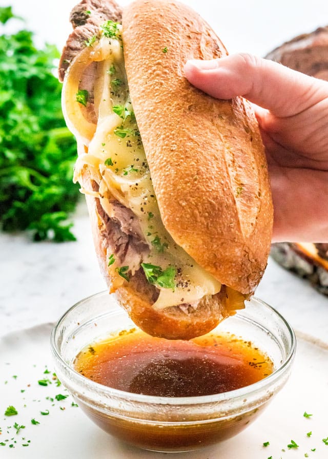 French Dip Sandwich being dipped in au jus