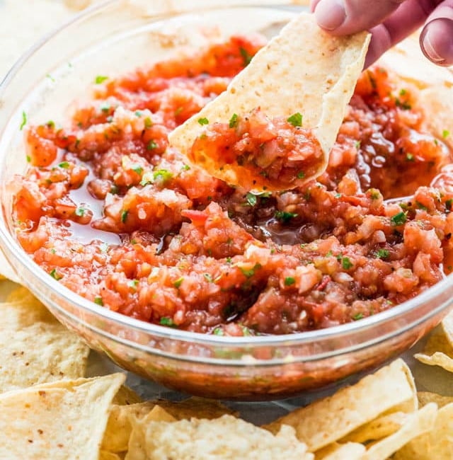 side view shot of a hand scooping up some salsa on a tortilla chip
