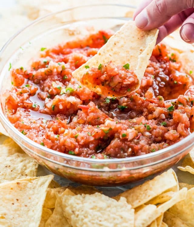 side view shot of a hand scooping up some salsa on a tortilla chip