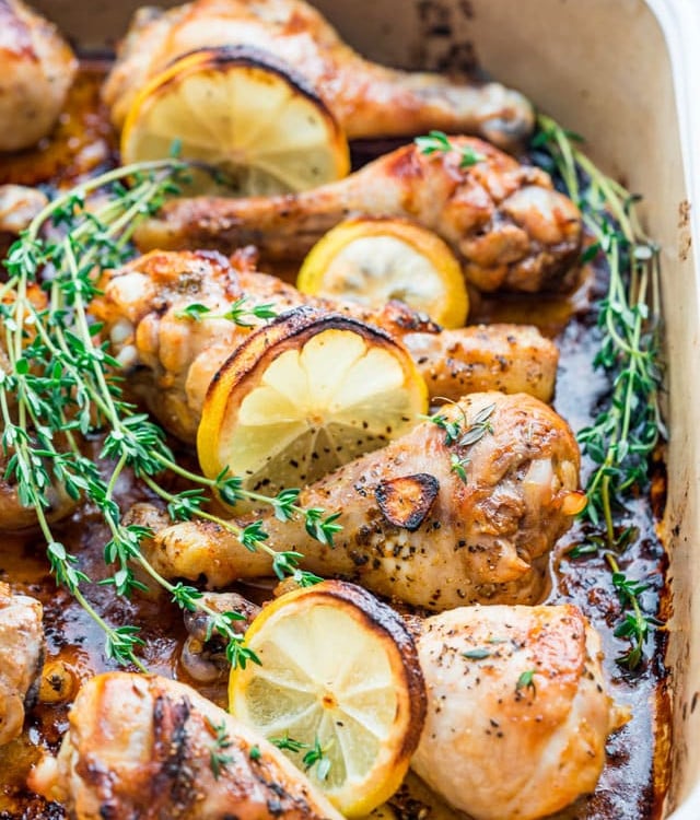 side view shot of lemon garlic chicken legs in a pot with lemon slices and fresh thyme
