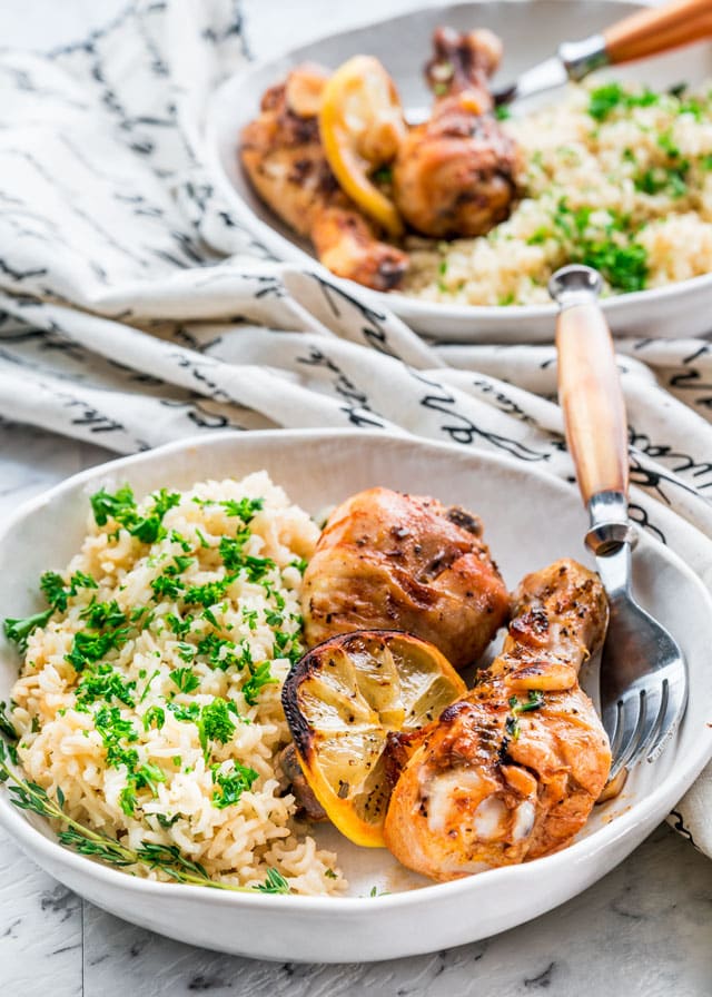 2 chicken legs roasted with lemons and herbs in a plate with rice