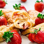 side view shot of strawberry cheesecake crescent rolls on a plate, one ripped in half exposing the center