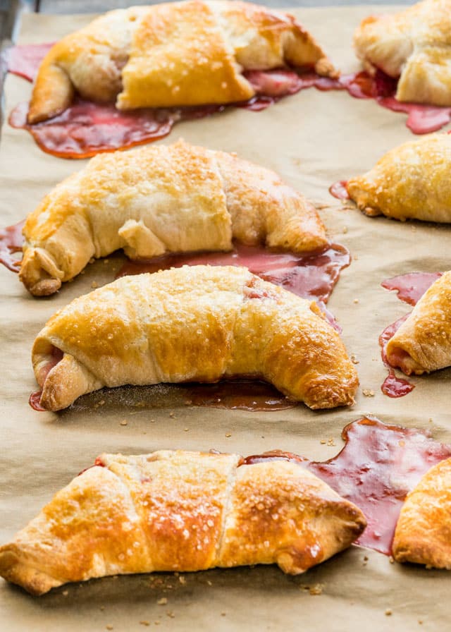 a pan of freshly baked crescents with strawberry jam oozing out