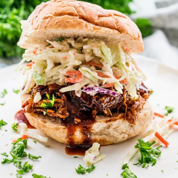side view shot of pulled pork topped with coleslaw on a bun