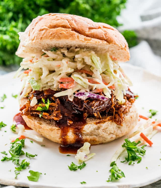 side view shot of pulled pork topped with coleslaw on a bun
