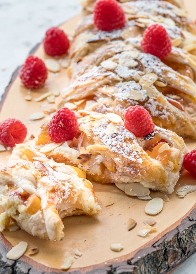 a piece of strudel with a bite taken out of it topped with fresh raspberries and almonds