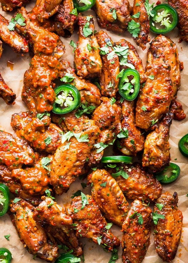overhead of chicken wings covered in red chimichurri topped with jalapenos
